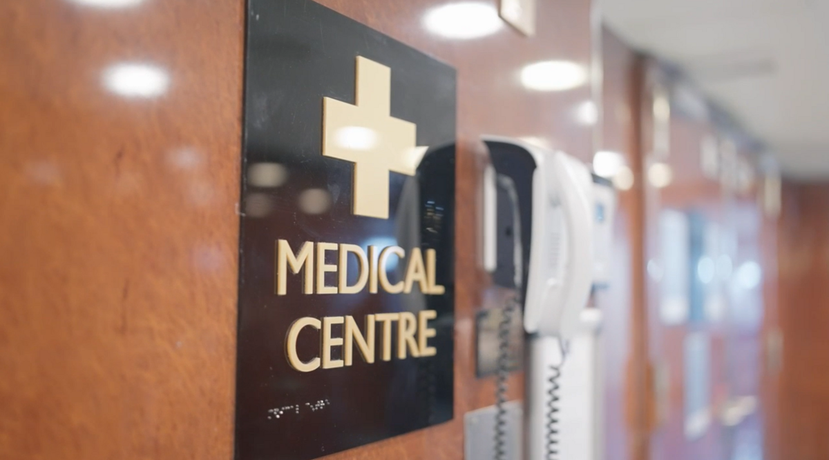 A wall-mounted sign with a gold cross and the words Medical Centre beside two telephones in a corridor with soft lighting.