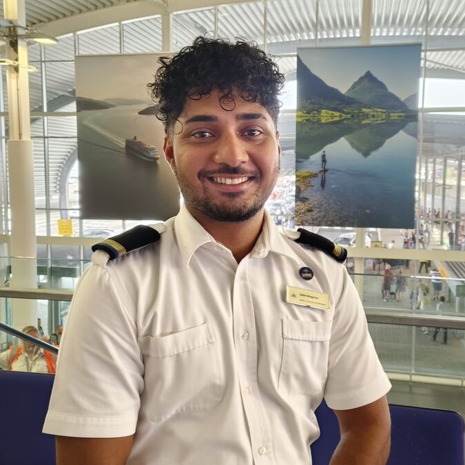 Cruise ship assistant crew services manager in uniform standing in modern cruise terminal, welcoming crew and supporting embarkation experience and crew service operations