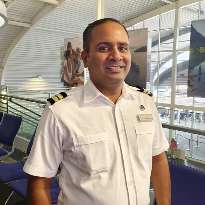 Crew Services Manager in uniform standing in cruise terminal, supporting crew travel, embarkation coordination and welfare services for shipboard teams