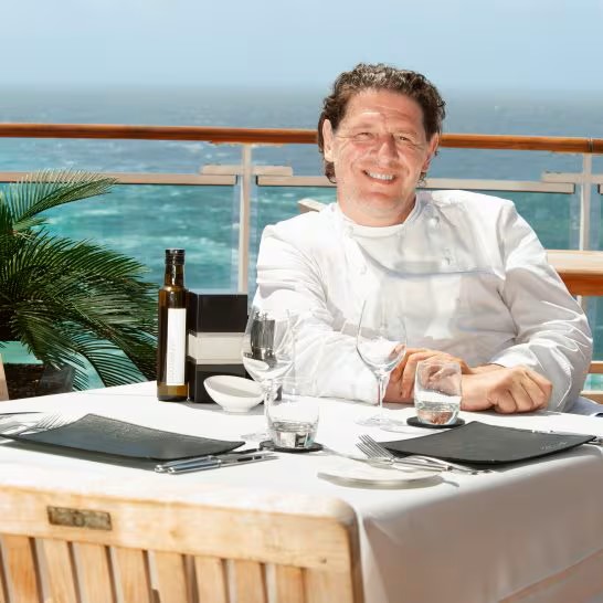Marco Pierre White aboard a P&O Cruises ship in an ocean-view dining setting, representing rewarding chef careers and life at sea.