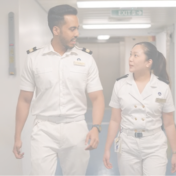 Two P&O Cruises officers walk through a ship corridor, discussing onboard operations and career development.