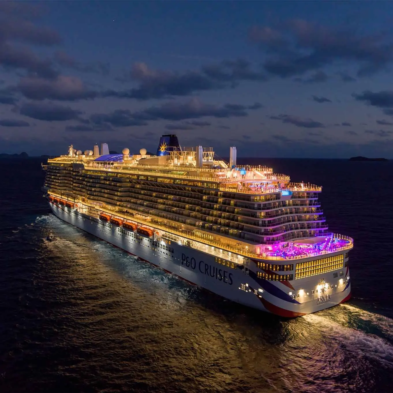 P&O Cruises ship Arvia sailing at night with illuminated guest areas and open decks visible across the vessel. The image represents the operational environment of a Night Duty Manager, overseeing guest services, shipboard operations and overnight incident response while maintaining a safe and seamless guest experience at sea.